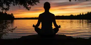 Person meditating by a tranquil lake at sunset, finding peace amidst grief in the US